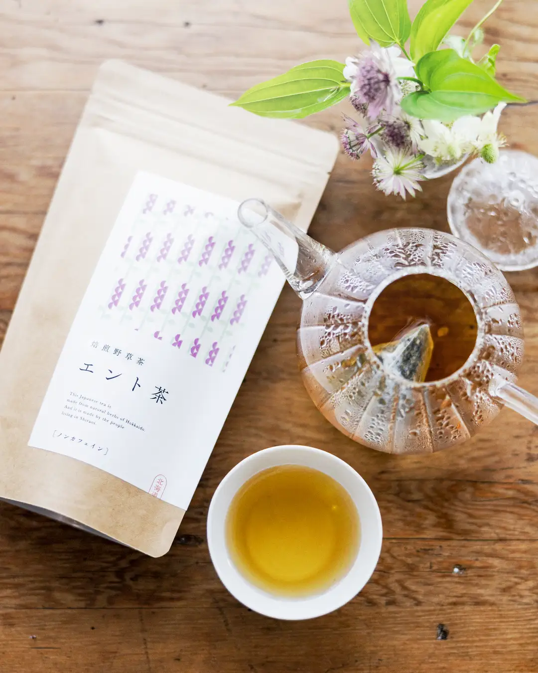  ティータイムを想起させる、エント茶のパッケージと淹れたてのお茶が入ったポット・カップ
